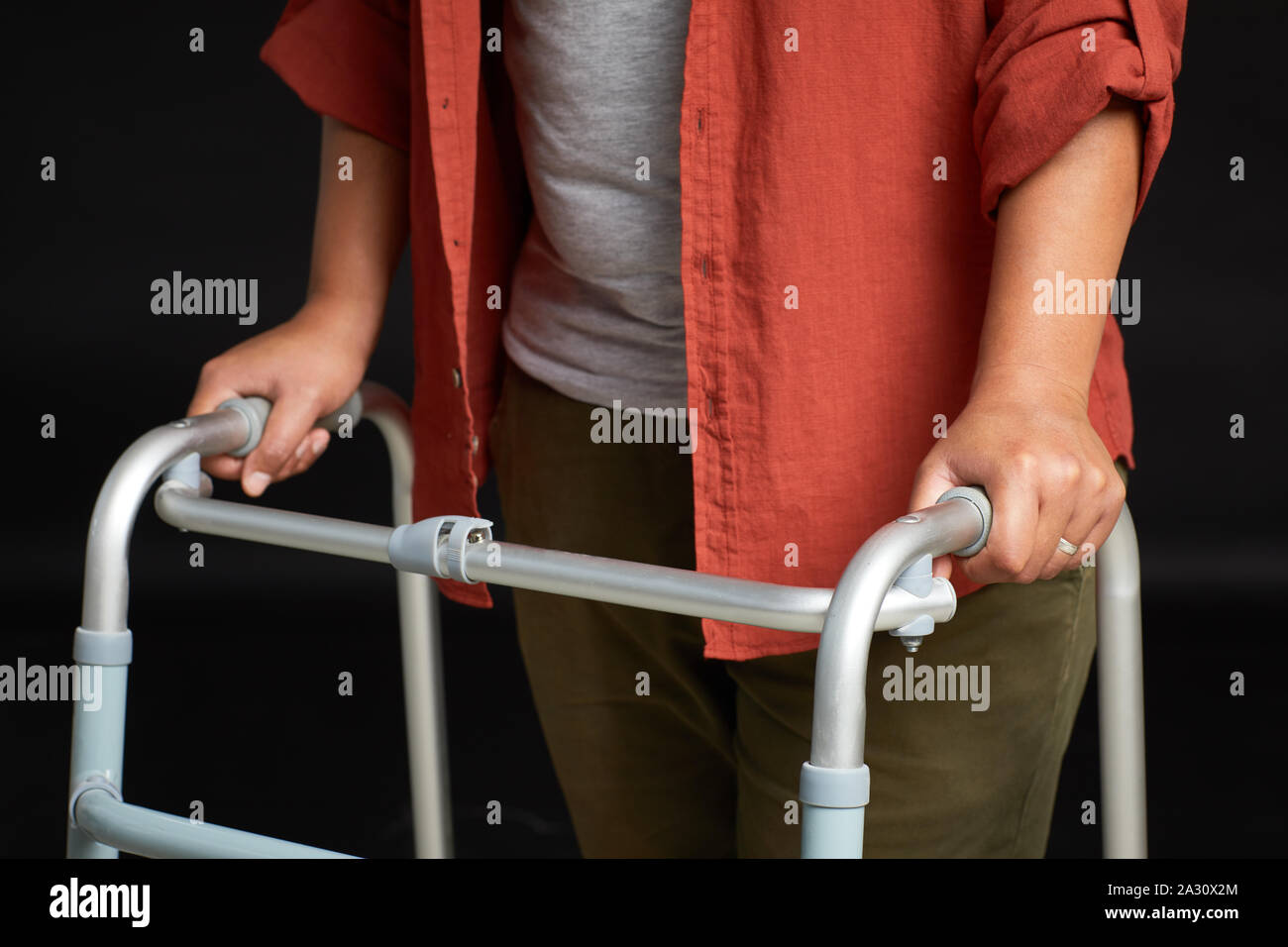 Close-up di giovane donna in piedi e appoggiato sullo scuotipaglia ella cercando di camminare isolati su sfondo nero Foto Stock