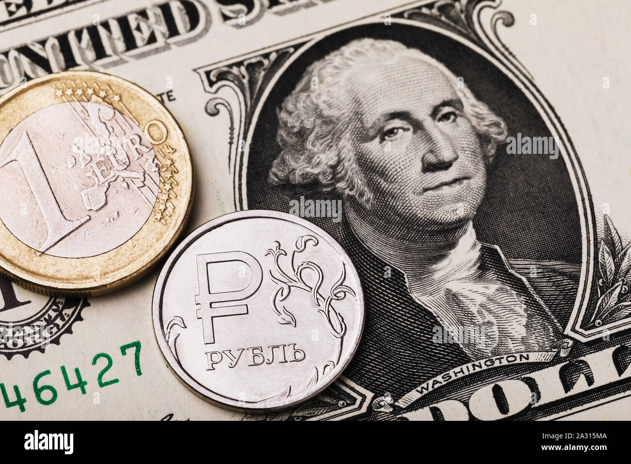 Moneta 1 euro e 1 rublo russo contro lo sfondo di un dollaro. Sulla moneta è la scritta in lettere in russo rublo Foto Stock
