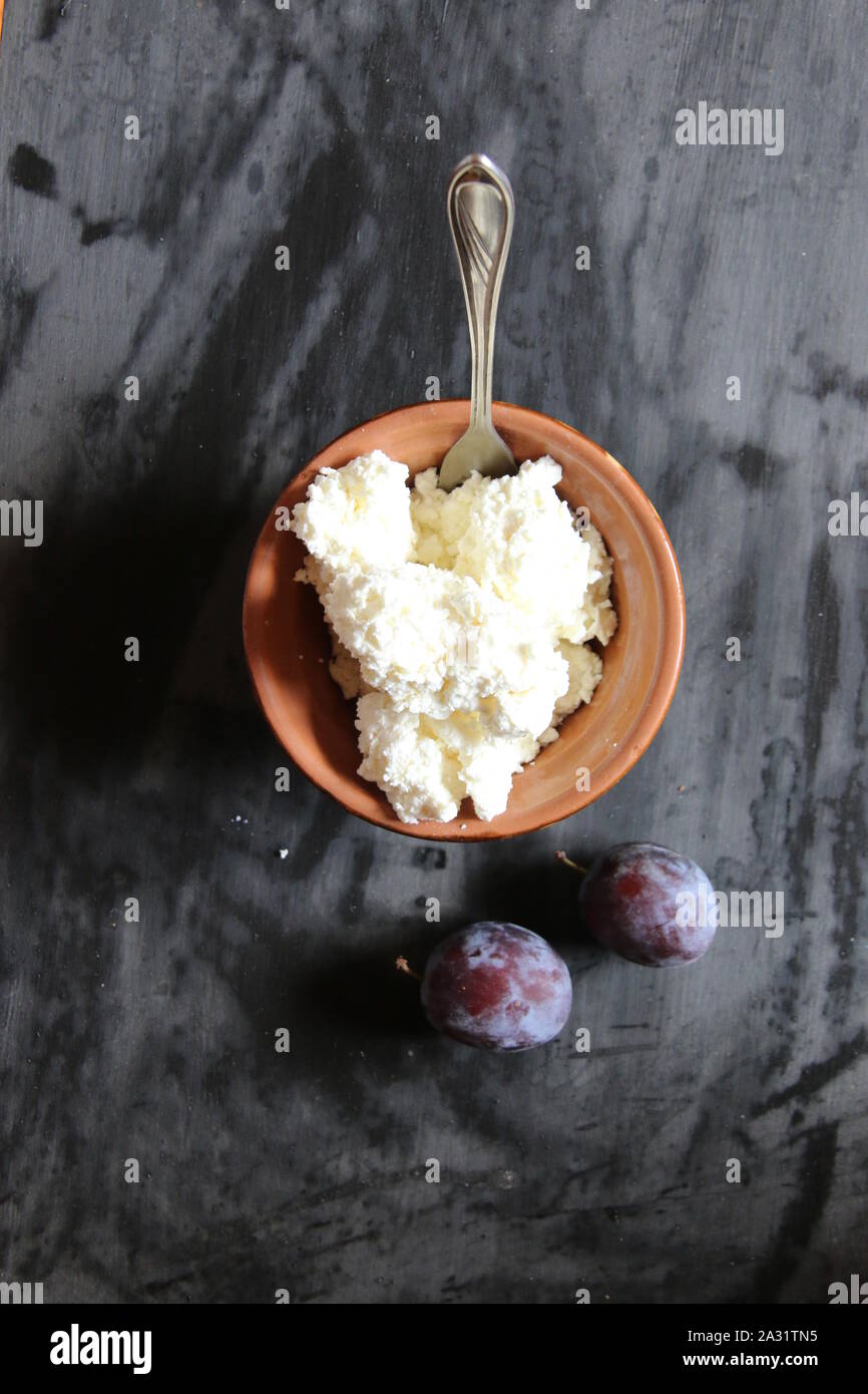 Gli agricoltori, formaggio di ricotta o formaggio nella ciotola sul tavolo e le prugne Foto Stock