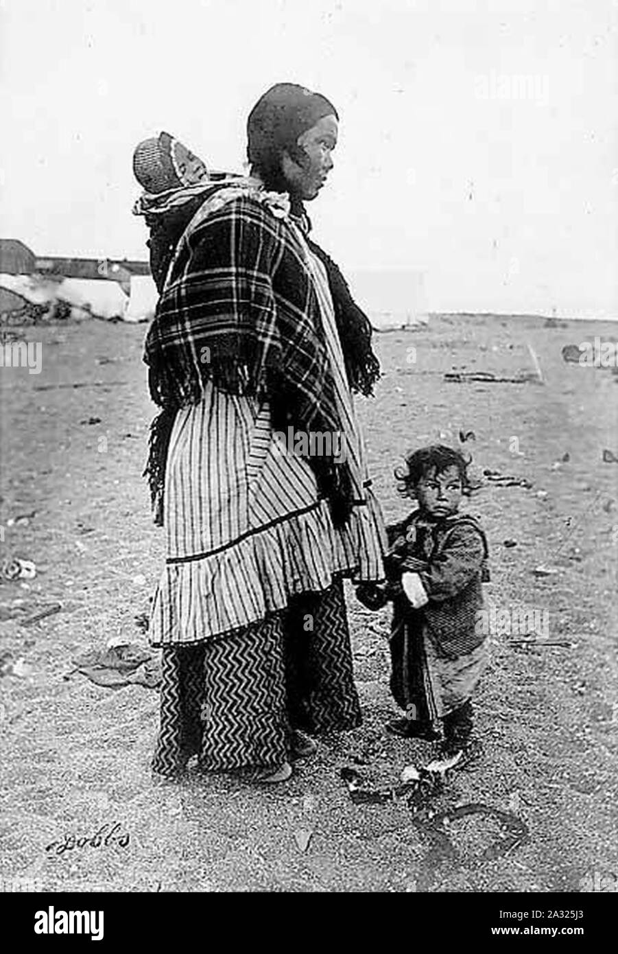 Eschimese donna che indossa il vestito e scialle permanente sulla spiaggia  con bambino bambino portando sulla sua schiena Alaska tra 1901 e 1911  (AL+CA 42 Foto stock - Alamy
