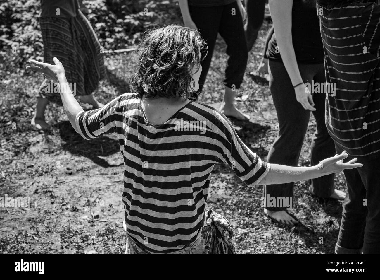 Un angolo alto e visualizzazione monocromatica di una donna che indossa una maglietta a strisce durante un ritiro all'aperto dove le persone cercano illuminismo e guida spirituale. Foto Stock