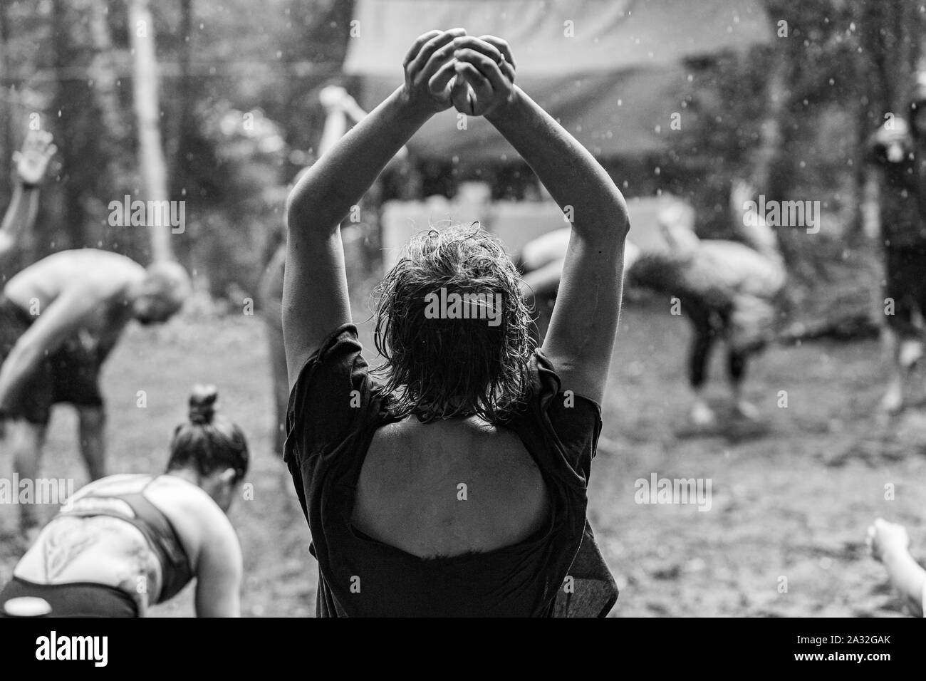 Un vicino la visualizzazione monocromatica di un libero-spirited donna, visto da dietro con le braccia sollevate durante un libero e giocoso il gruppo di musica da ballo nel bosco, con copy-spazio. Foto Stock