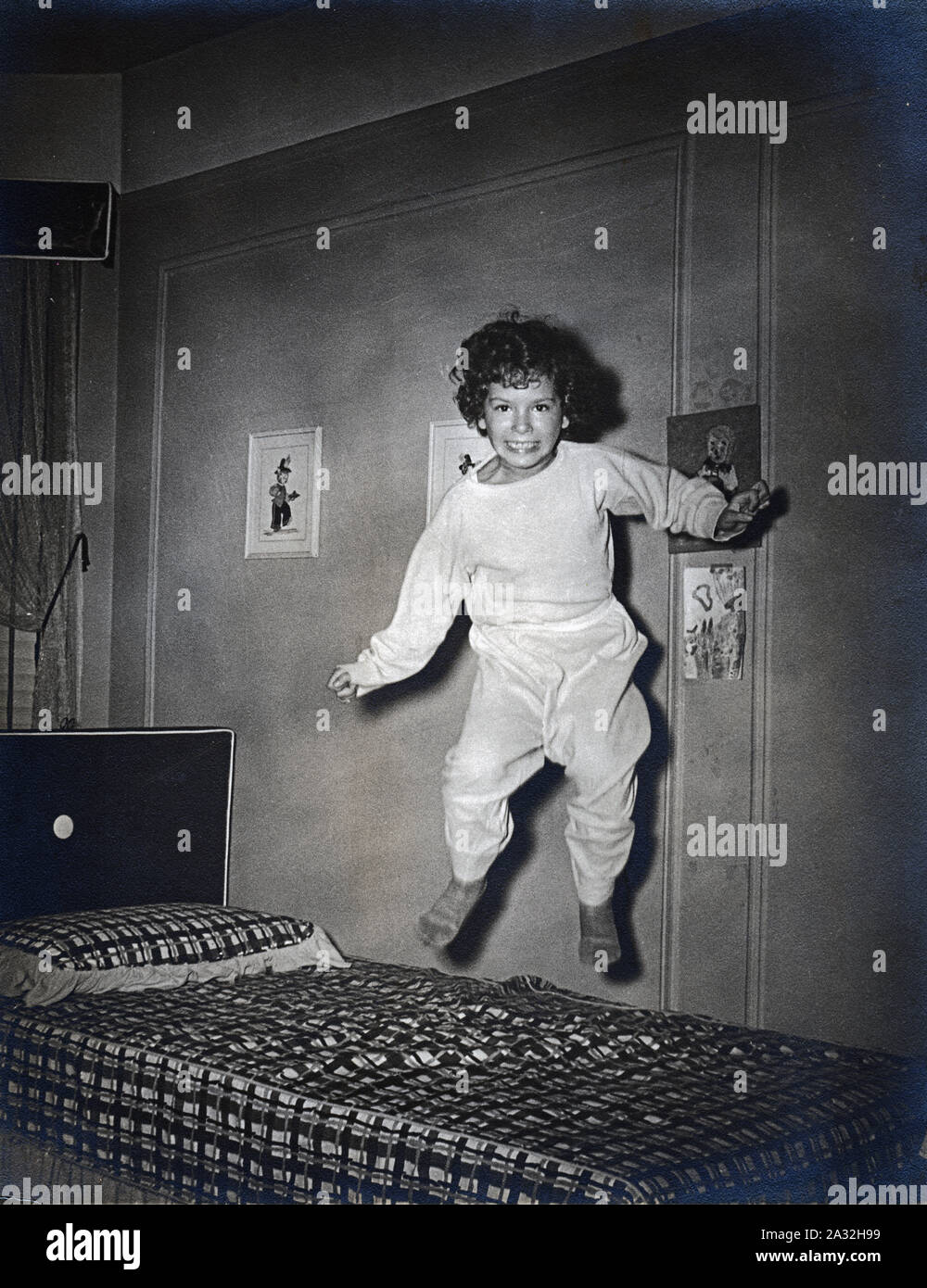 Un immagine vintage di una ragazza di saltare su e giù sul suo letto, circa 1956. Foto Stock