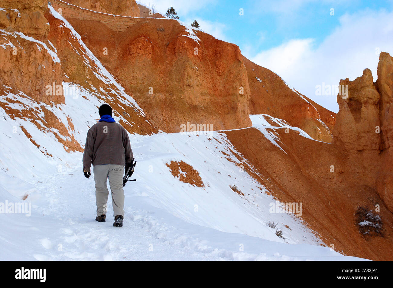 Giovane uomo trekking sul sentiero innevato in rocce rosse in montagna Bryce Canyon Foto Stock