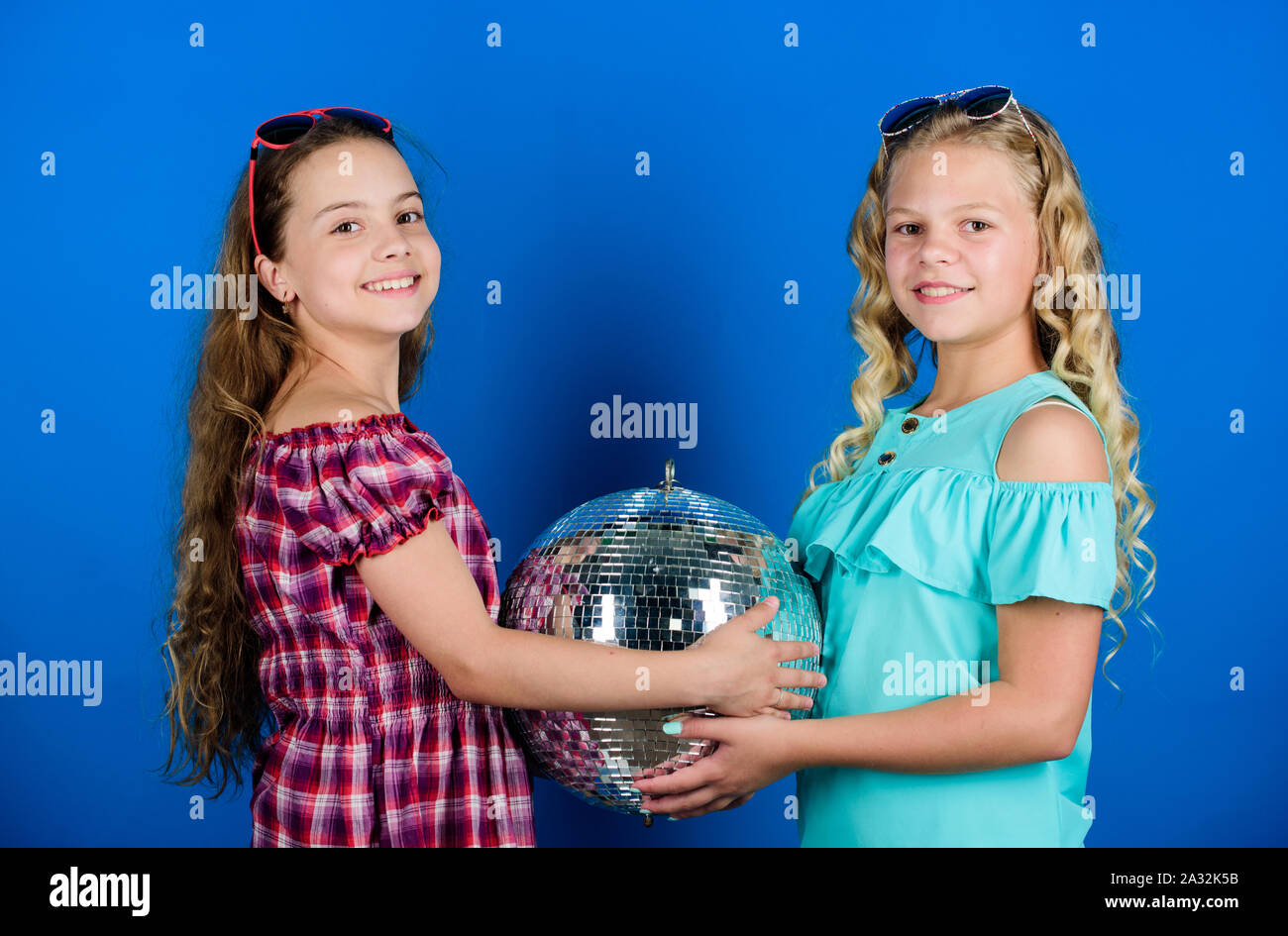 Sorelle amici con palla da discoteca. Iniziare a parte. Allegro kids tenere palla da discoteca. Discoteca danze. Musica retrò. Gli specchi riflettenti discoteca luci di atmosfera. Holiday celebrazione. Concetto di intrattenimento. Foto Stock