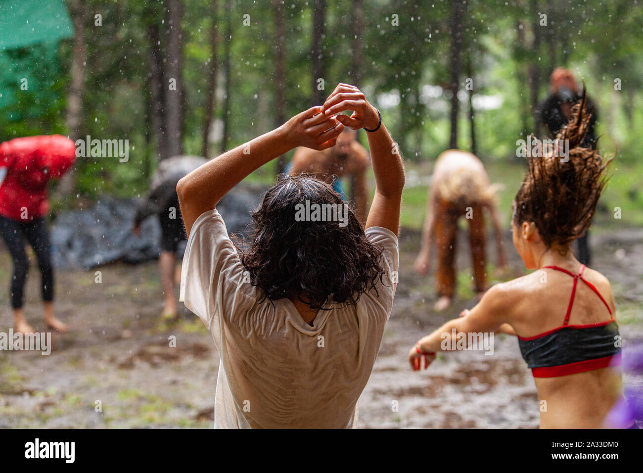 Un grande gruppo di uomini e donne sperimentano memore di danza e meditazione in un bosco fangoso durante la cancellazione di una natura di ritiro. Foto Stock