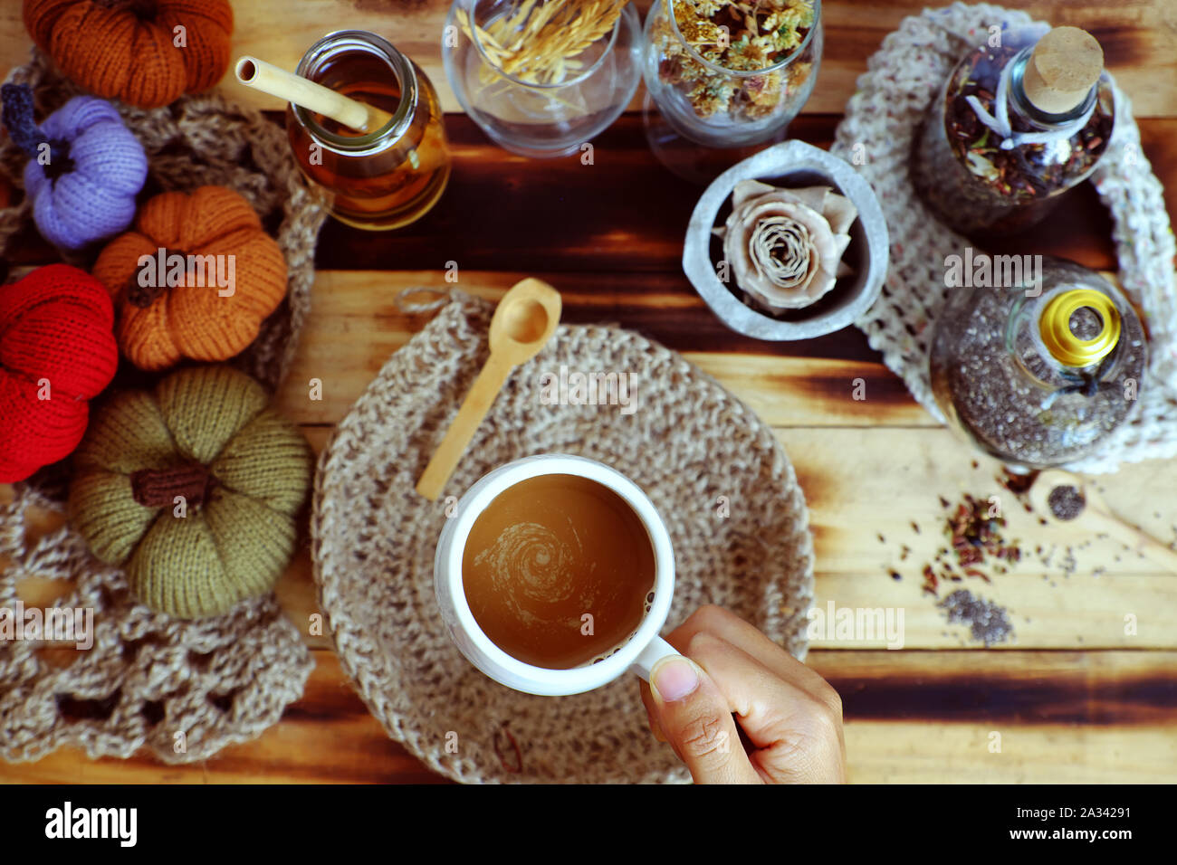 Top vista donna mano tenere tazza di caffè del mattino su sfondo autunno con decorazione stagionale tavolo ornamento per la casa decorazione come zucca, tela di piatto burlap Foto Stock