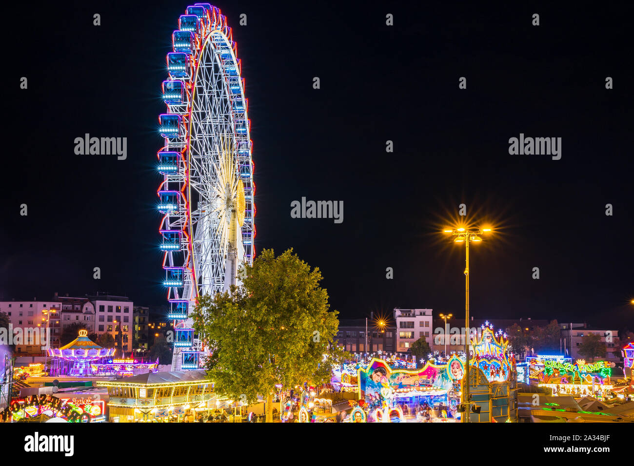 Stoccarda, Germania, 3 ottobre 2019, Canstatter wasen oktoberfest fair illuminata di notte con molti giostra ruota grande e offre cibo attrarre c Foto Stock