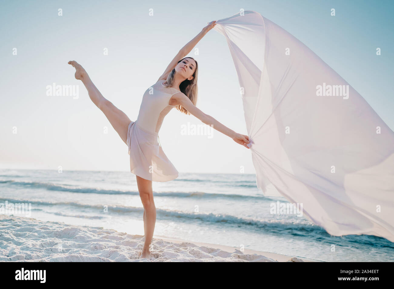 Giovane ballerina balletto di ballo sulla riva del mare con tessuto di seta  che fluttua nel vento Foto stock - Alamy