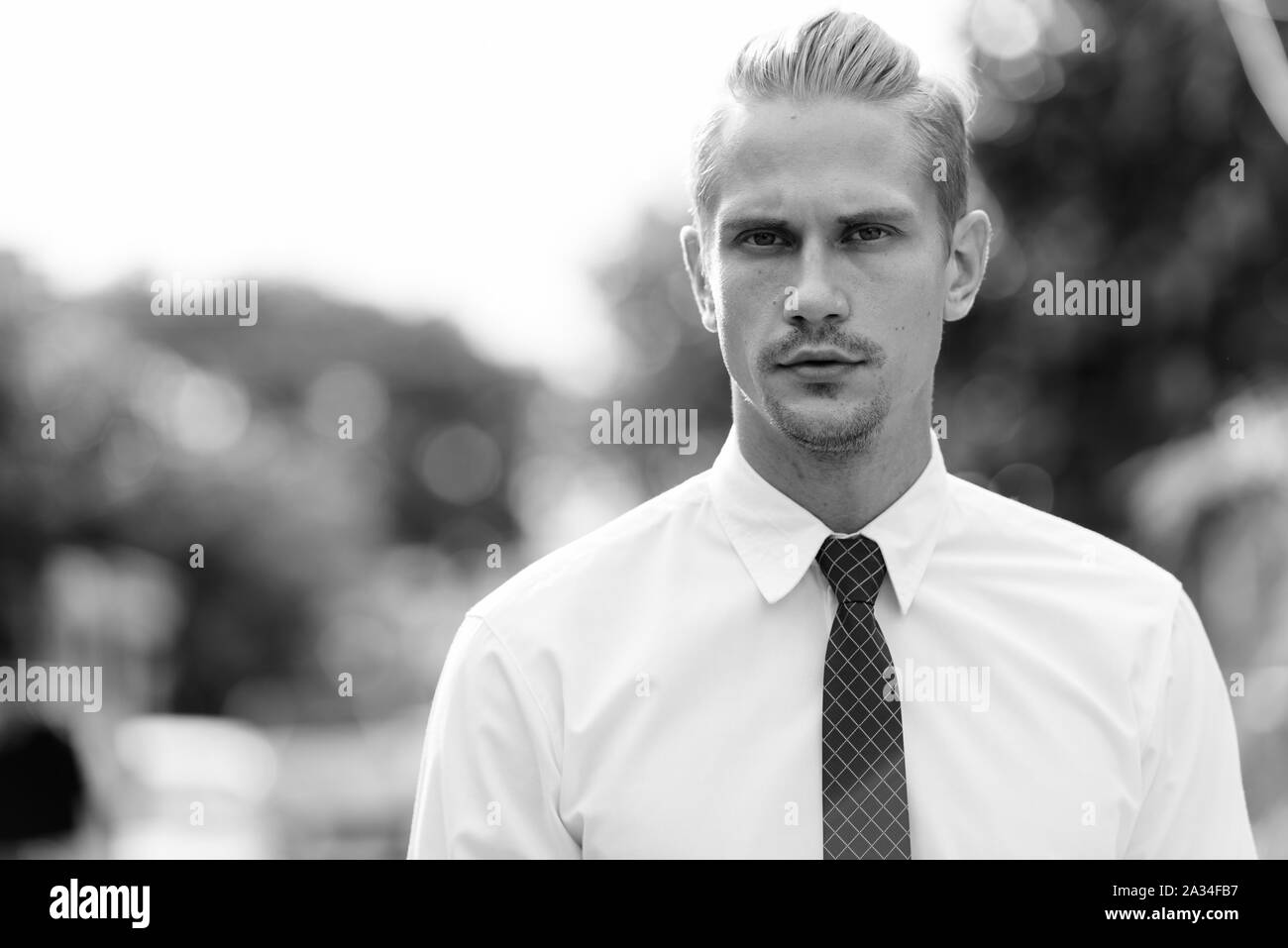 Ritratto di bel giovane uomo in piedi all'esterno in bianco e nero Foto Stock