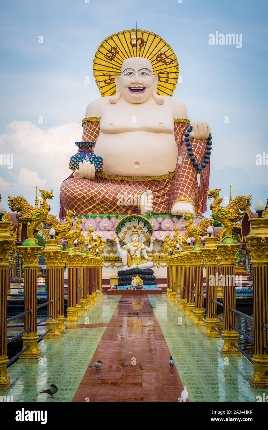 Sorridente gigante o felice statua del Buddha con cielo blu nel tempio buddista ( wat Plai Laem ), Koh Samui, Thailandia. Foto Stock