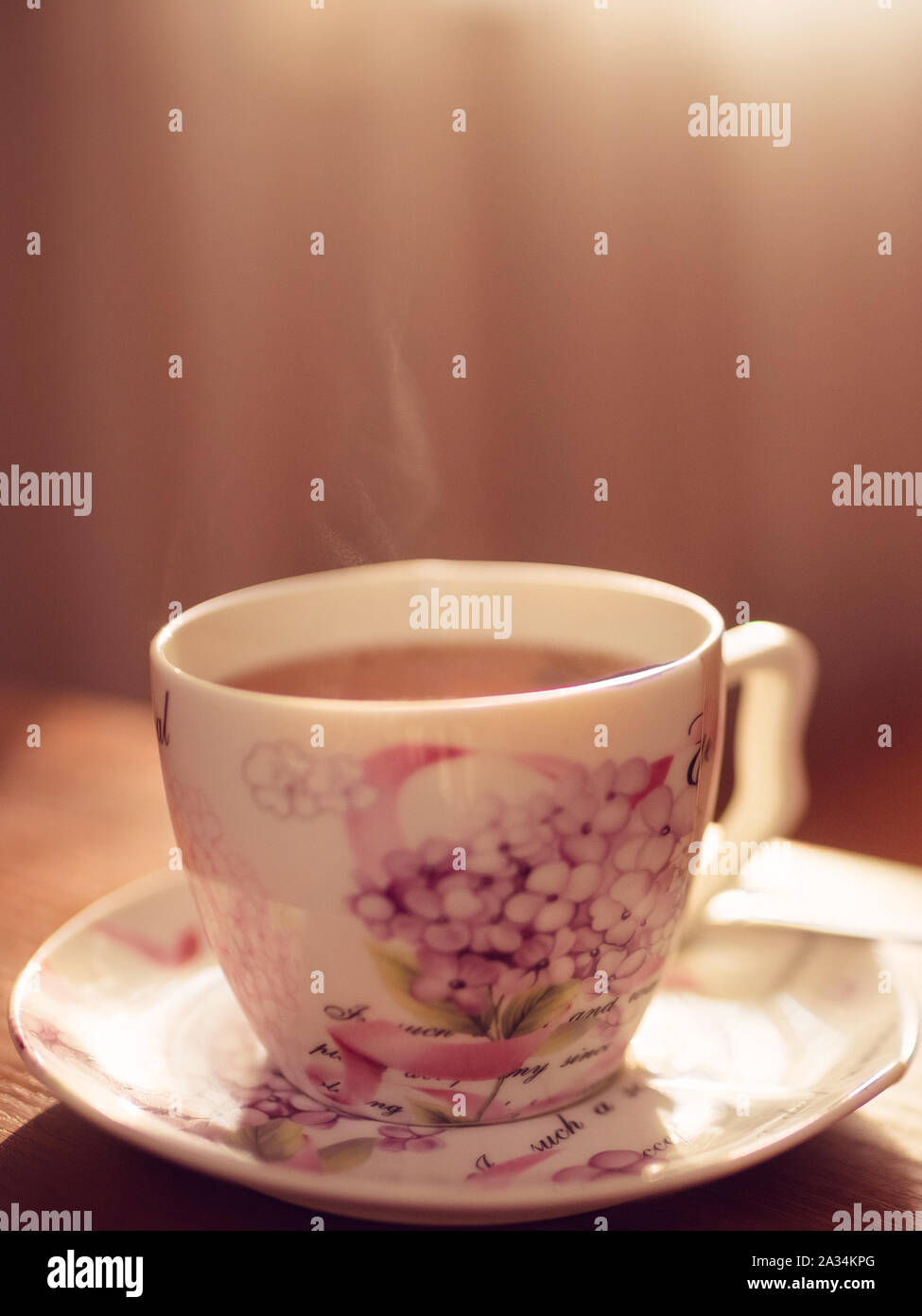 Il tè nero in un elegante vintage tazza di porcellana con il vapore sul tavolo Foto Stock