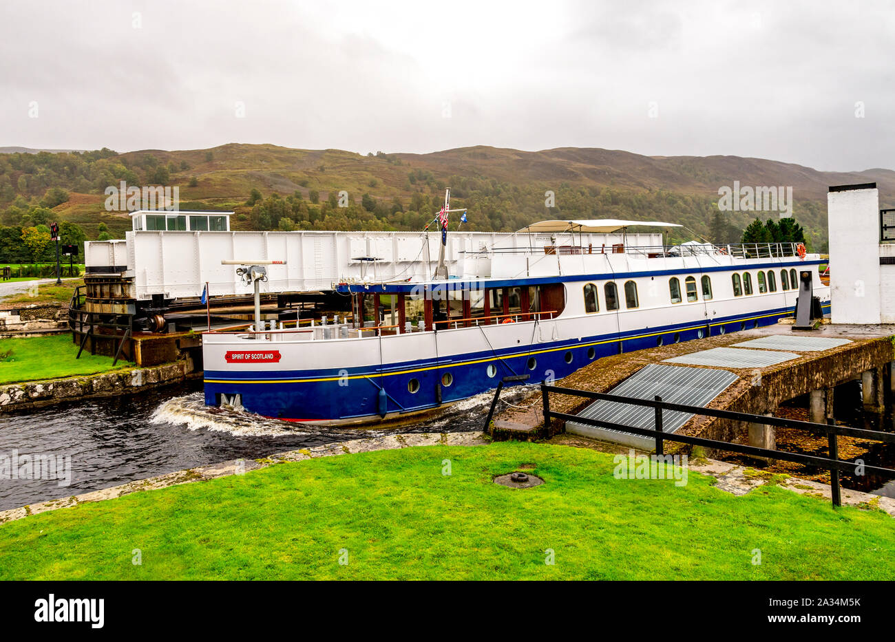 Una barca che passa attraverso il aperto il ponte girevole e immettendo il Caledonian Canal da Loch Oich vicino Aberchalder, Scozia Foto Stock