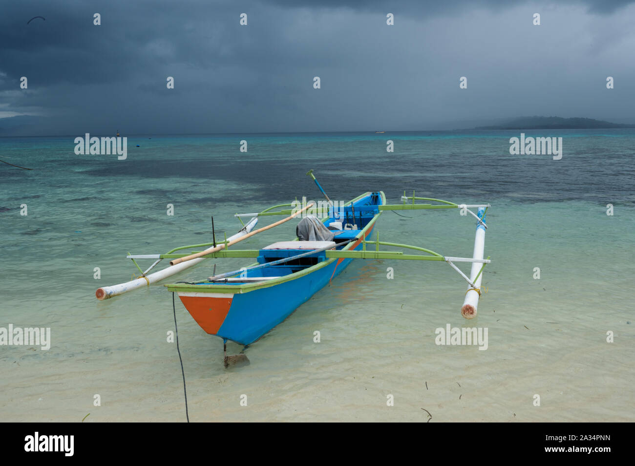 Canoa Outrigger sotto la pioggia tropicale tempesta, Gangga isola di Sulawesi, Indonesia. Foto Stock