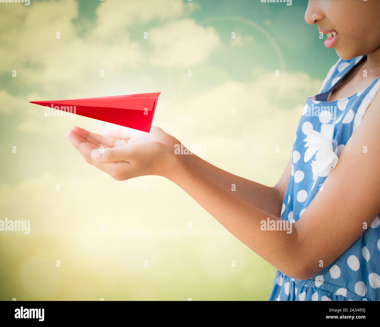 Bambina avendo cura e mantenimento degli aeromobili rosso carta origami con lo sfondo della natura Foto Stock