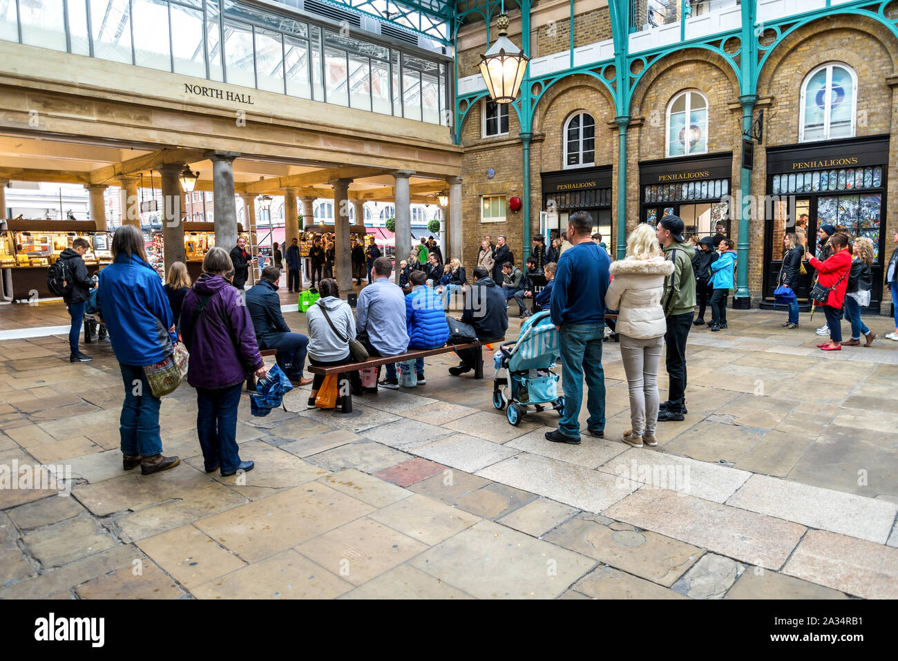 Turisti e visitatori di guardare una street performance in Covent Garden area dello shopping, London, Regno Unito Foto Stock