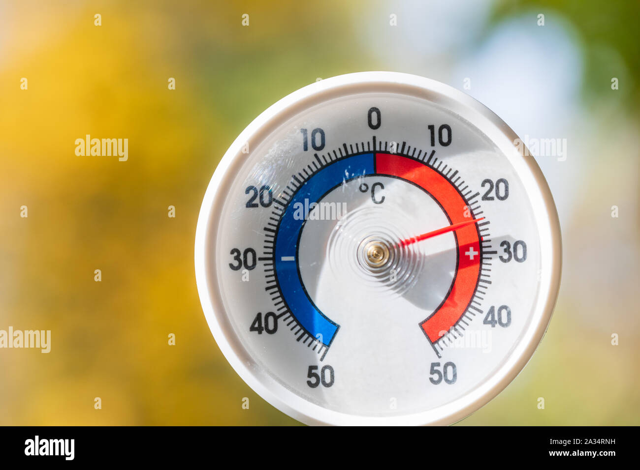 Termometro da esterno con scala Celsius che mostra la temperatura calda, offuscata Foglie di autunno visto in background - calda estate indiana o il riscaldamento globale concep Foto Stock