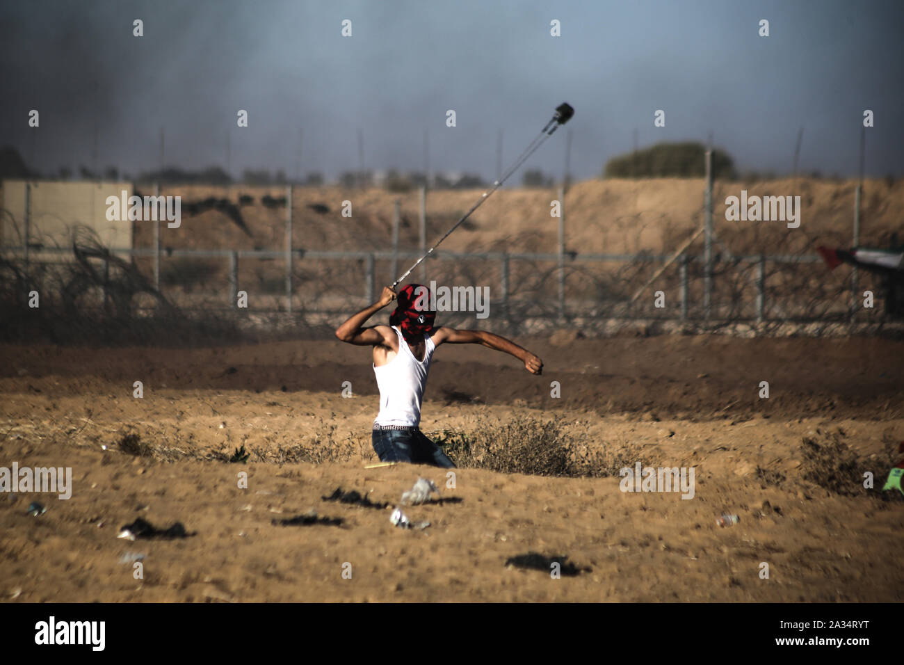 Un dimostrante palestinese utilizza un slingshot per scagliare pietre durante un anti-Israele dimostrazione per chiedere la fine di anni di assedio su Gaza sul confine Israel-Gaza nel sud GazaGaza striscia. Foto Stock