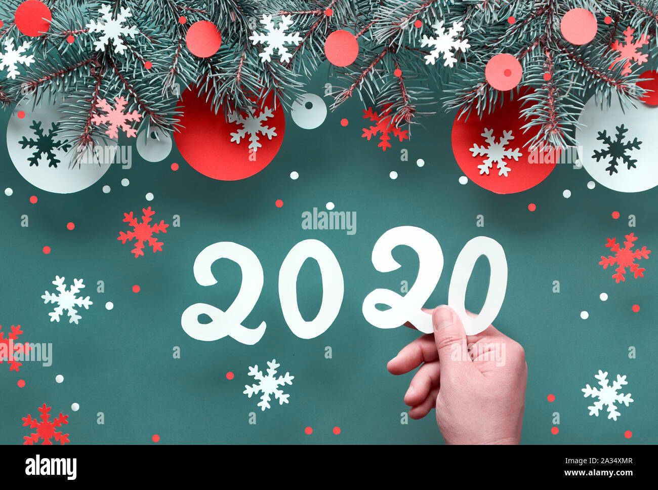 Mano azienda numero 2020, Natale sfondo con ramoscelli di abete rosso e bianco decorazioni di carta. Appartamento laico, vista dall'alto sul verde scuro lo sfondo della carta. Foto Stock