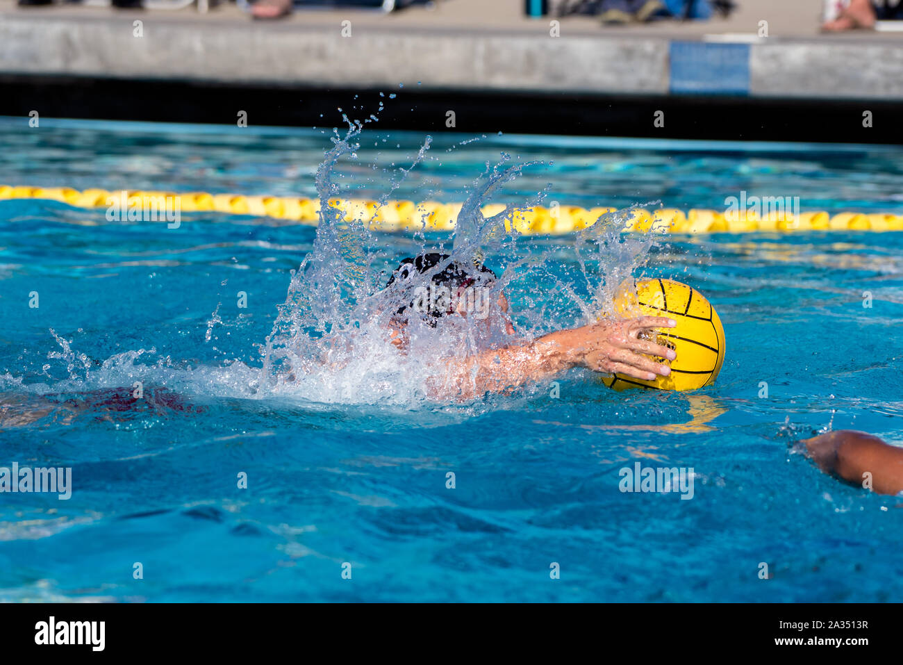 Acqua Varisty giocatore di polo nel cappuccio nero nuoto mantenendo la sfera alla sua portata in piscina. Foto Stock