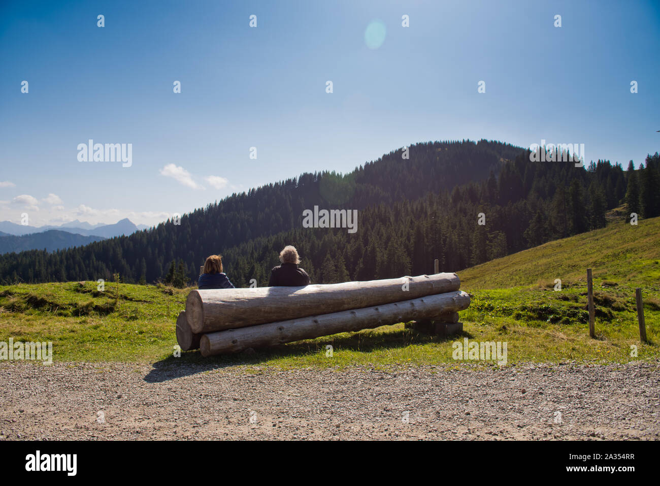 Due persone sono seduti insieme su un banco di log e guardando le montagne. Foto Stock