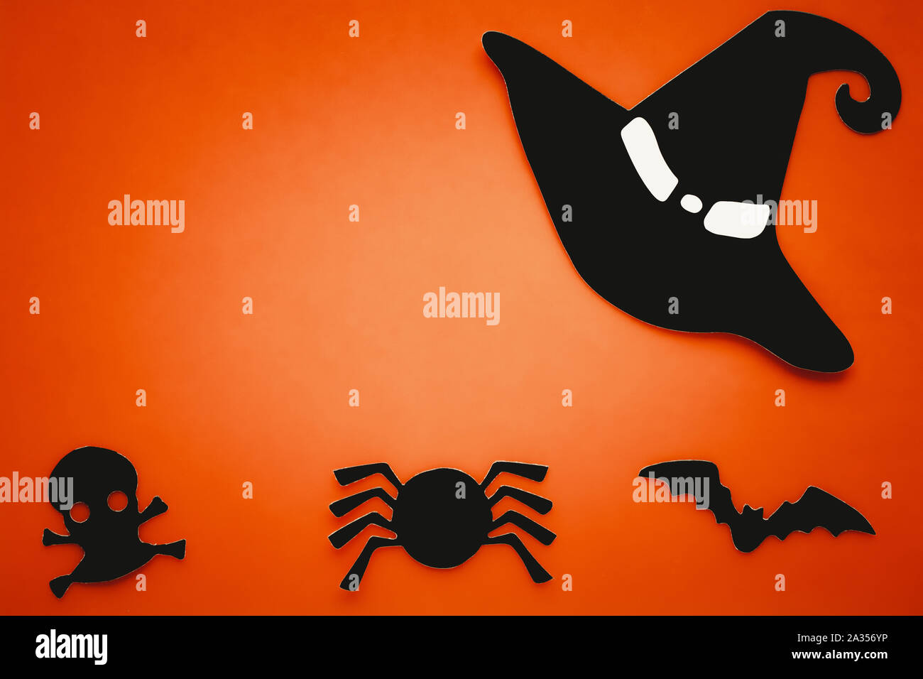 Sfondo arancione con silhouette nera del ragno, bat, cranio, witch hat. Scheda di Halloween, composizione della carta. Arte astratta. Invito in arancione brillante Foto Stock