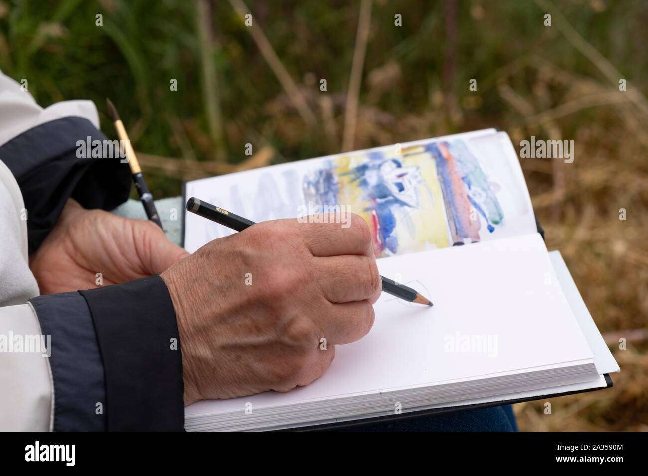 Disegno a mano in sketchbook, godendo di pensionamento al di fuori del disegno casual da indossare abiti caldi Foto Stock