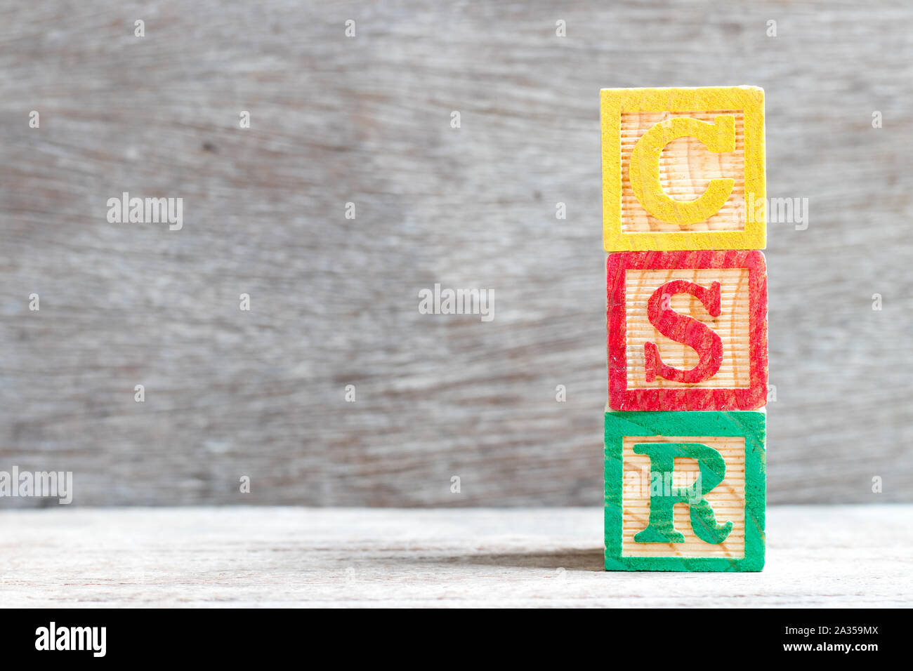 Colore blocco lettera nella parola CSR (abbreviazione di corporate social responsibility) su uno sfondo di legno Foto Stock