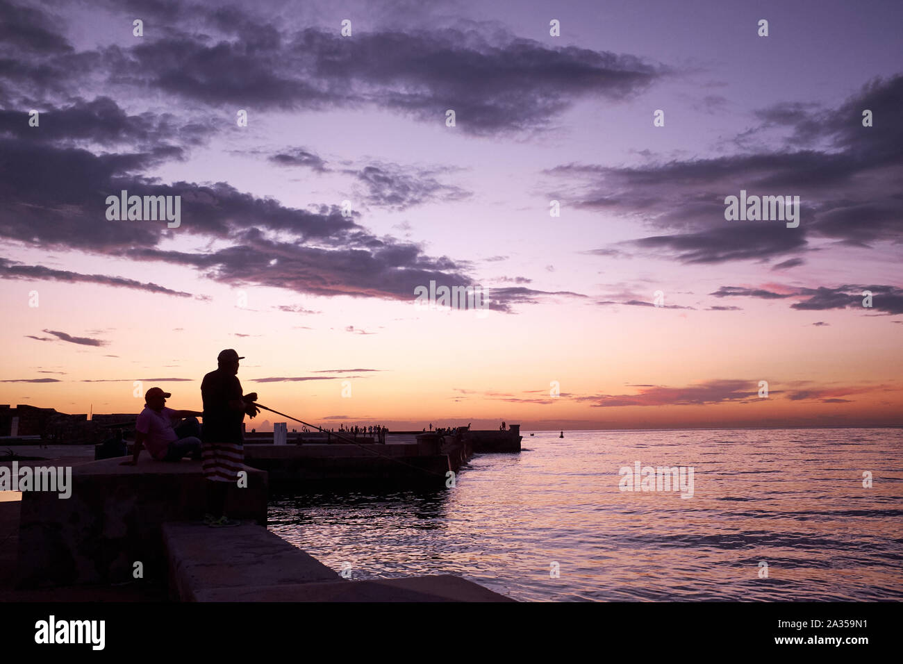 Gli uomini la pesca al tramonto lungo la baia di l'Avana a l'Avana, Cuba Foto Stock