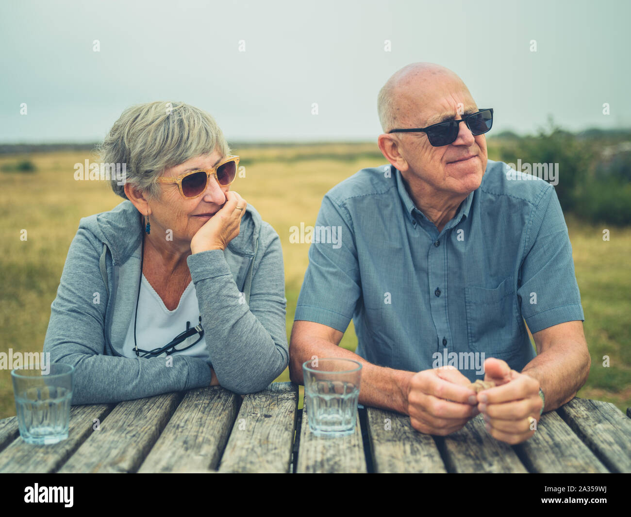 Una coppia senior sono seduti ad un tavolo da picnic all'aperto nella campagna Foto Stock