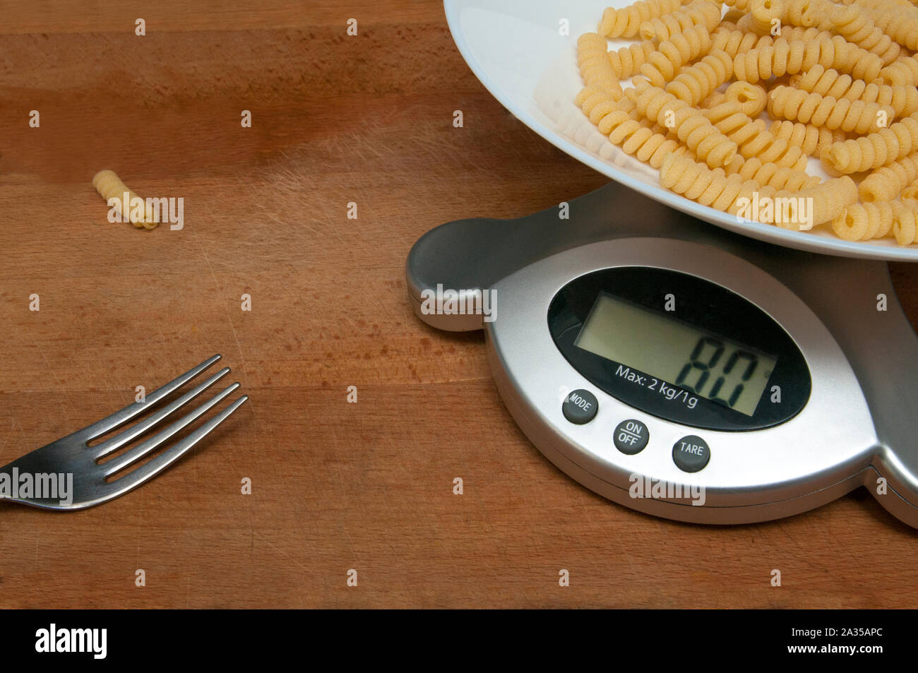 80 grammi di pasta in un piatto di una bilancia da cucina su un tagliere di  legno Foto stock - Alamy