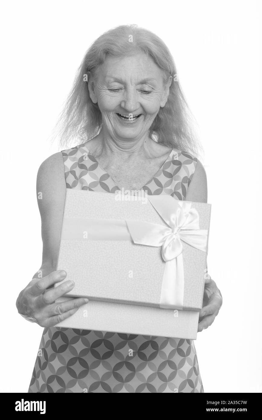 Studio shot di felice senior donna sorridente durante l'apertura della confezione regalo Foto Stock