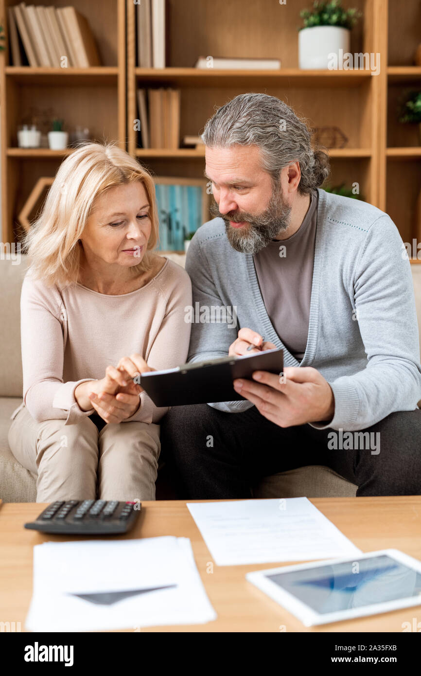 Uomo maturo e la donna la lettura di termini di contratto mentre vado a comprare una casa nuova Foto Stock