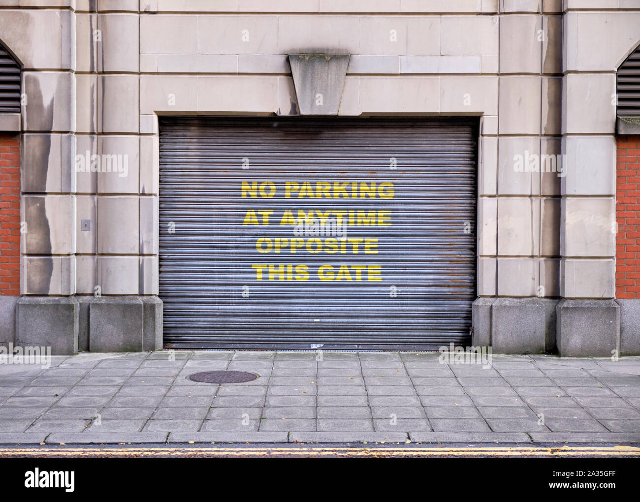 Symetric minima facciata di edificio con un metallo porta scorrevole garage con grande giallo scrivendo 'Nessun parcheggio in qualsiasi momento e di fronte a questo gate' Foto Stock