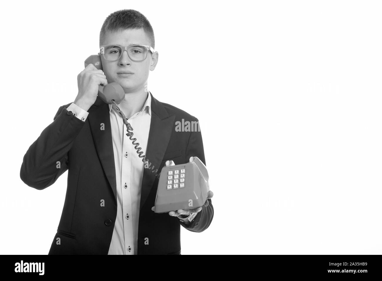 Studio shot del giovane imprenditore parlando sul vecchio telefono Foto Stock