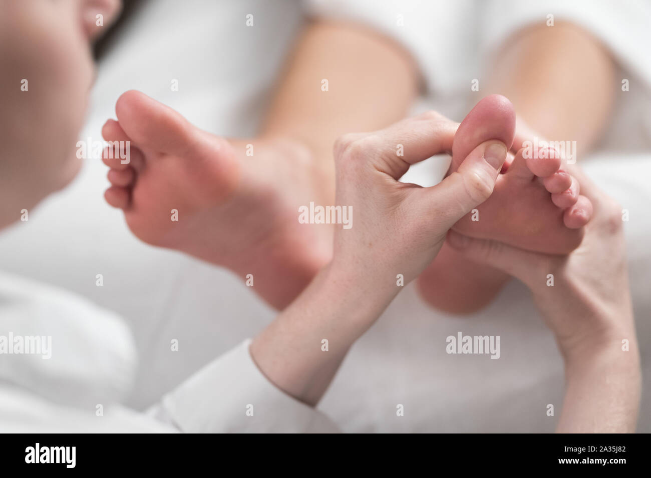 Professional masseur femmina dando riflessologia plantare per il piede della donna Foto Stock