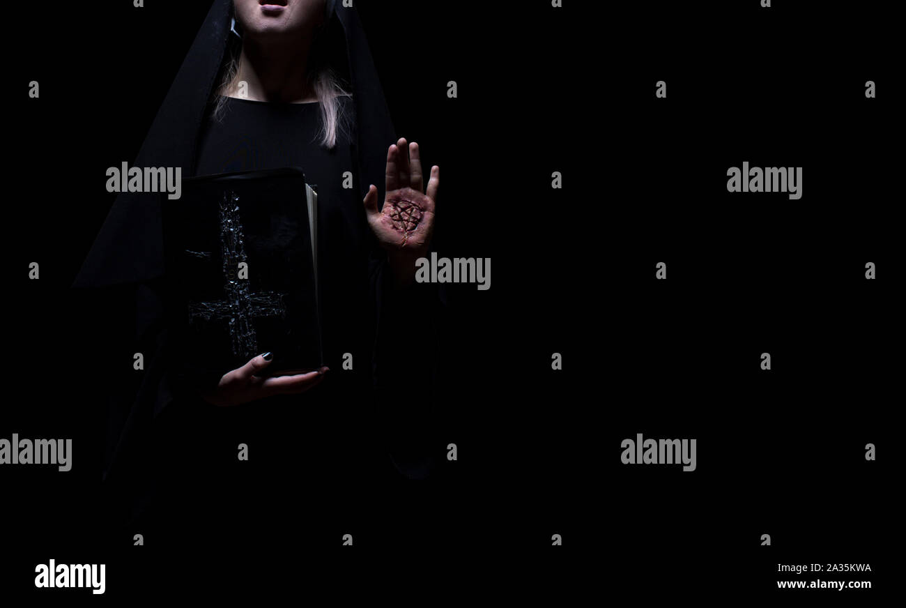 Strega che tiene un libro magico incantesimo con il simbolo del pentagramma in piedi. Halloween, mockup di concetto di magia nera. Foto Stock