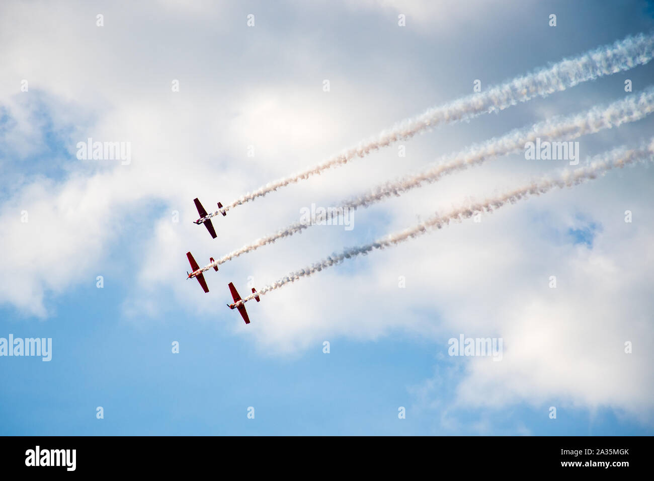 Acrobazia, air show. Il team di aeromobili di eseguire nel cielo con vecchi aerei e linee di disegno, il bianco delle nuvole e cielo blu Foto Stock