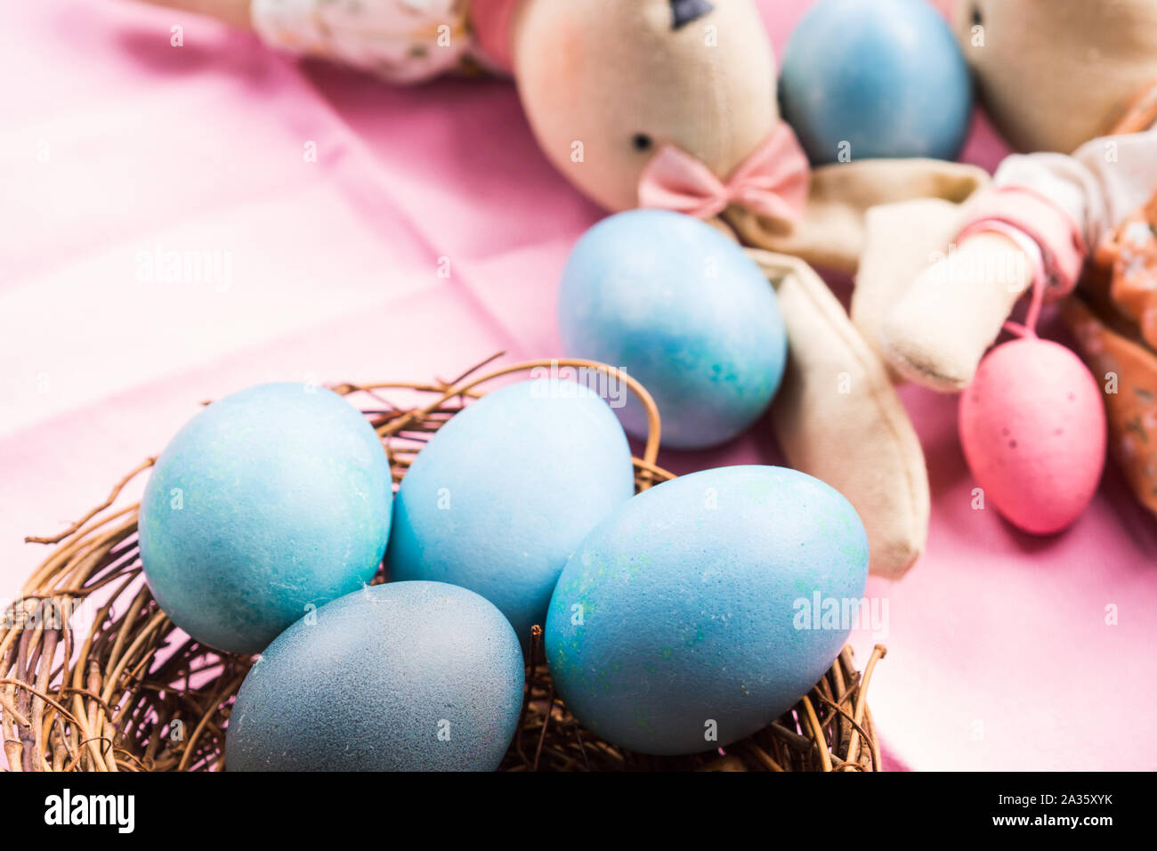 Rosa vacanze di pasqua concetto con bunny e colorate in blu le uova sode in un nido di vimini Foto Stock
