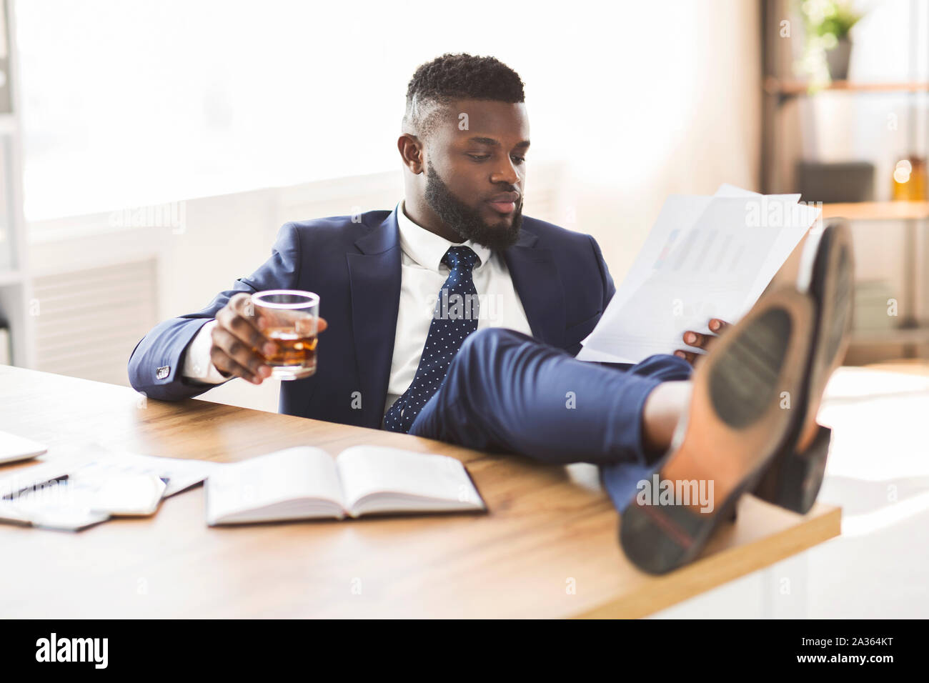 Ubriaco manager verifica in relazione alle vendite, tenendo in mano un bicchiere di Whiskey Foto Stock