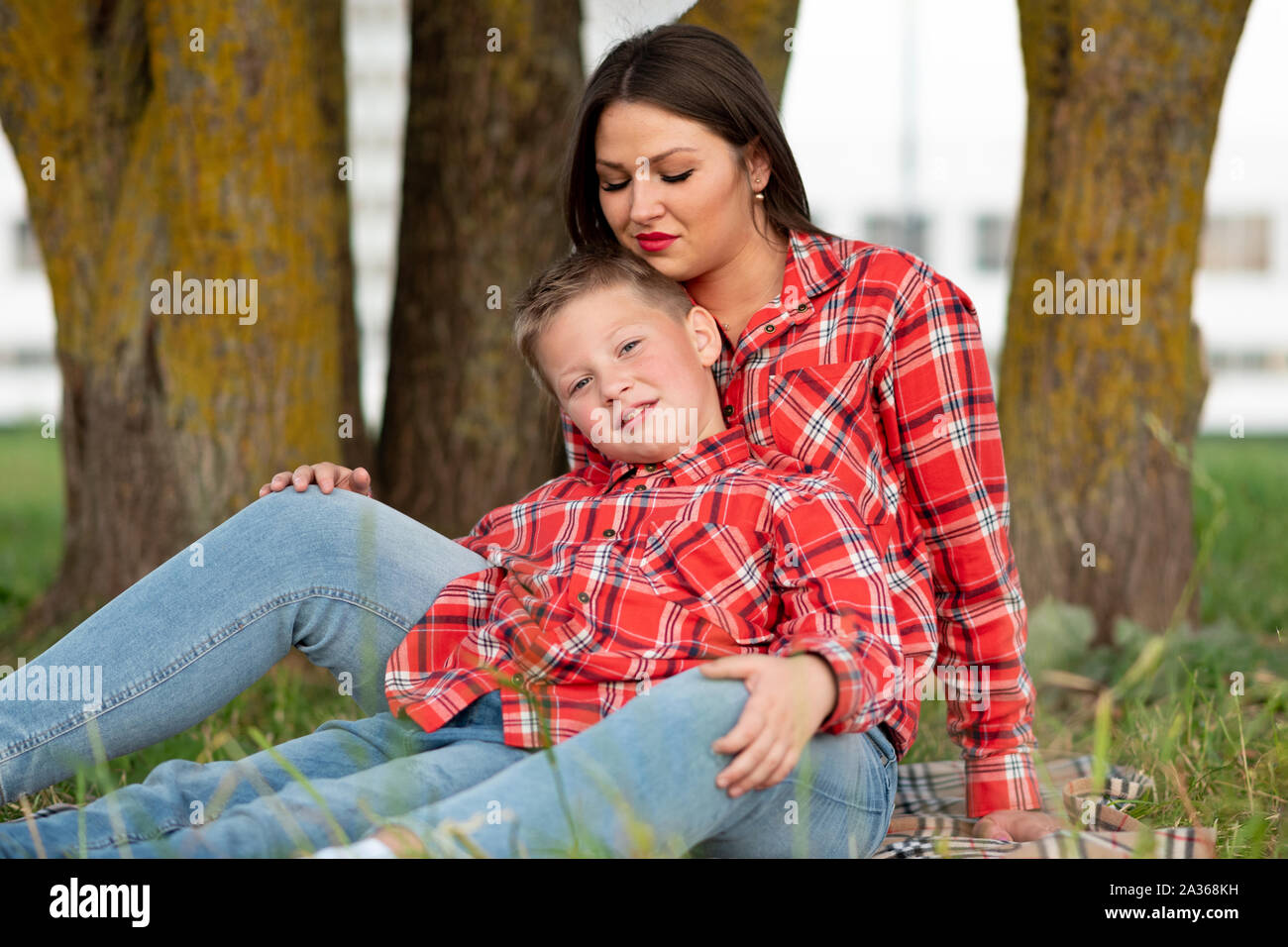 Madre e figlio seduti sul copriletto abbraccio delicatamente. Foto Stock
