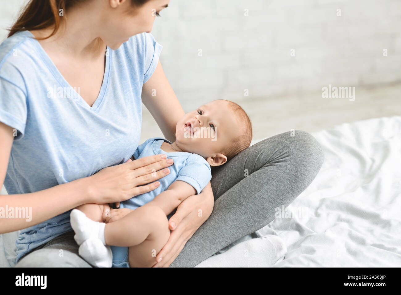 Giovane madre lulling i suoi adorabili baby boy su giri Foto Stock