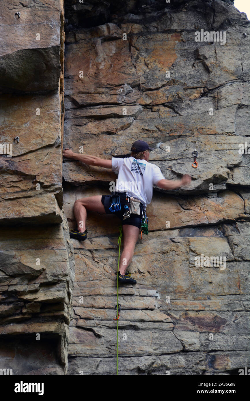 Un giovane maschio scalatore lavora il suo modo fino l'Anfiteatro scogliera a battuta la molla Trail a Pilot Mountain State Park in North Carolina. Foto Stock