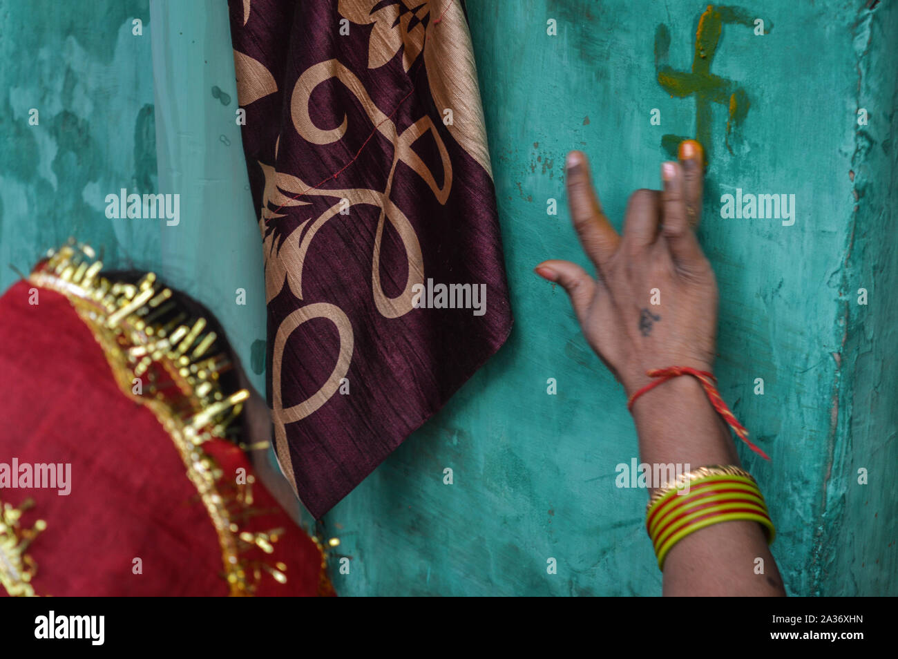 Signora mettendo la curcuma sulla parete blu in matrimoni indiani. Foto Stock