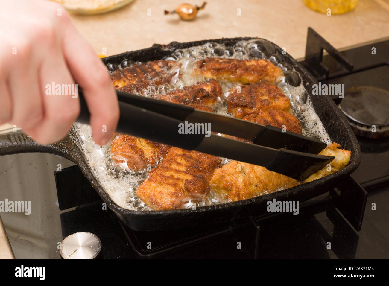 Pepite di cottura da freschi a base di carne di pollo su un caldo cast-padella di ferro Foto Stock