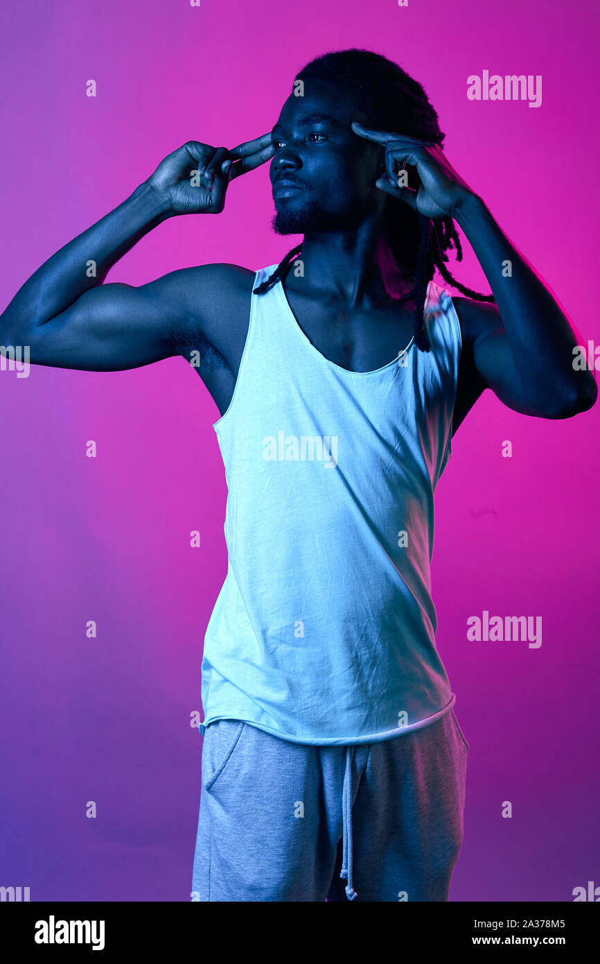 Musculat uomo bello con elegante dreadlocks toccando i suoi templi, gesto, il linguaggio del corpo, vicino la vista laterale verticale Foto Stock