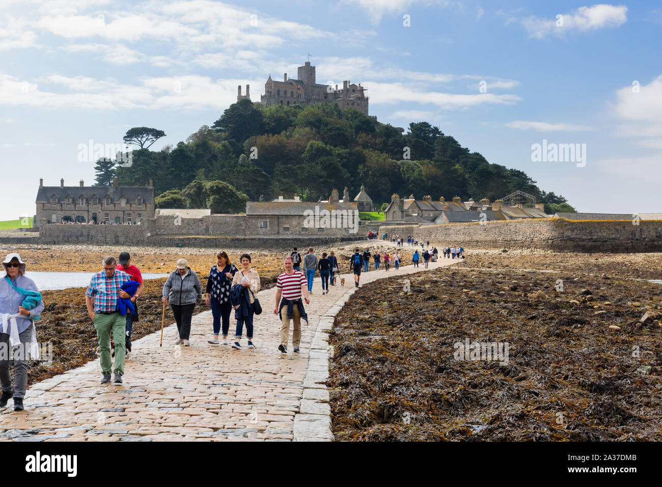 I visitatori e i turisti a piedi lungo la strada rialzata di marea a bassa marea tra Marazion e Saint Michaels Monte Isola in Cornovaglia Foto Stock