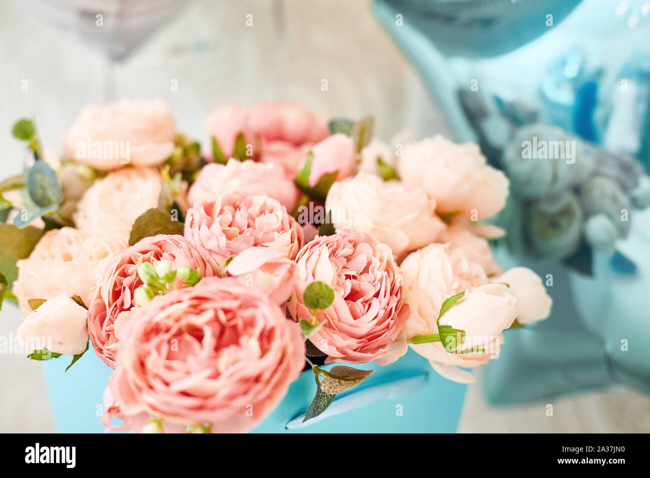 Composizione della rosa artificiale di peonie in una casella blu. cartolina. Foto Stock