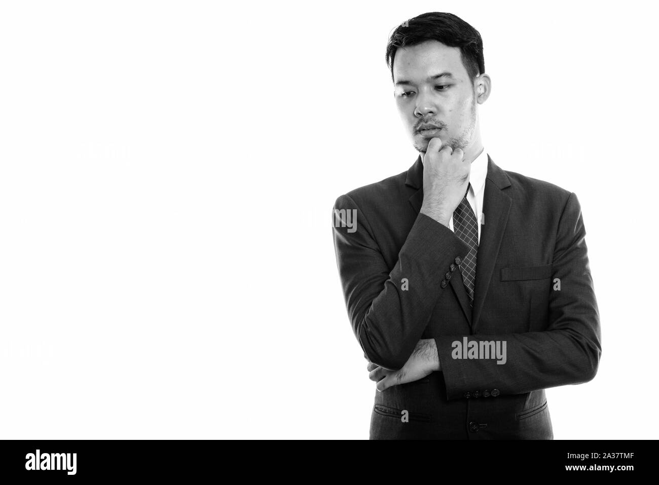 Studio shot del giovane imprenditore asiatici pensando mentre guardando verso il basso Foto Stock