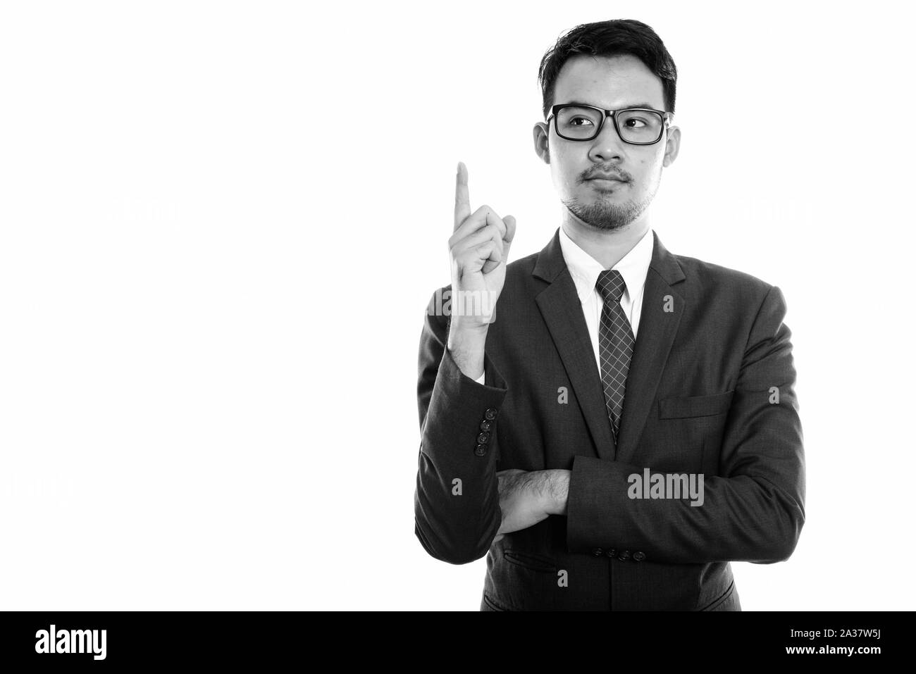 Studio shot del giovane imprenditore asiatico puntare il dito verso l'alto mentre si pensa Foto Stock